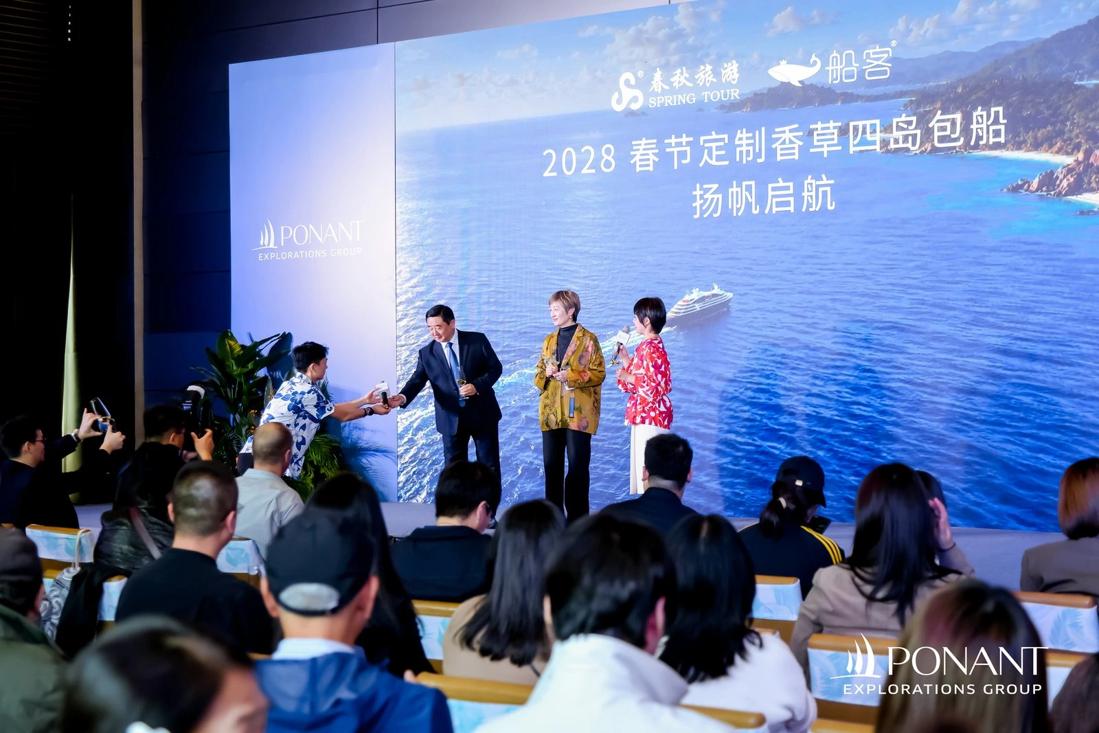 香草四岛包船推介会台上交流，工作人员向嘉宾递上话筒
