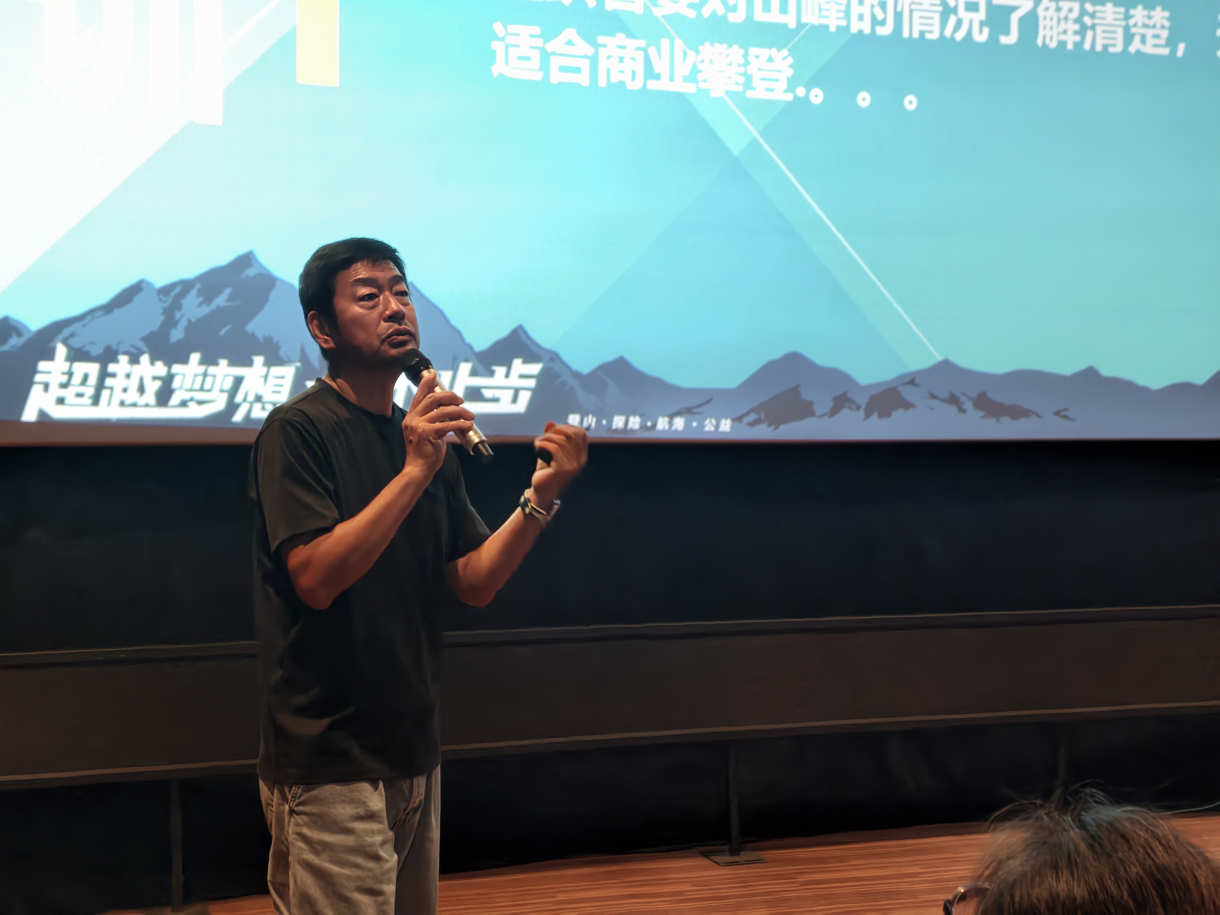 张梁在分享会上,身后大屏展示雪山画面